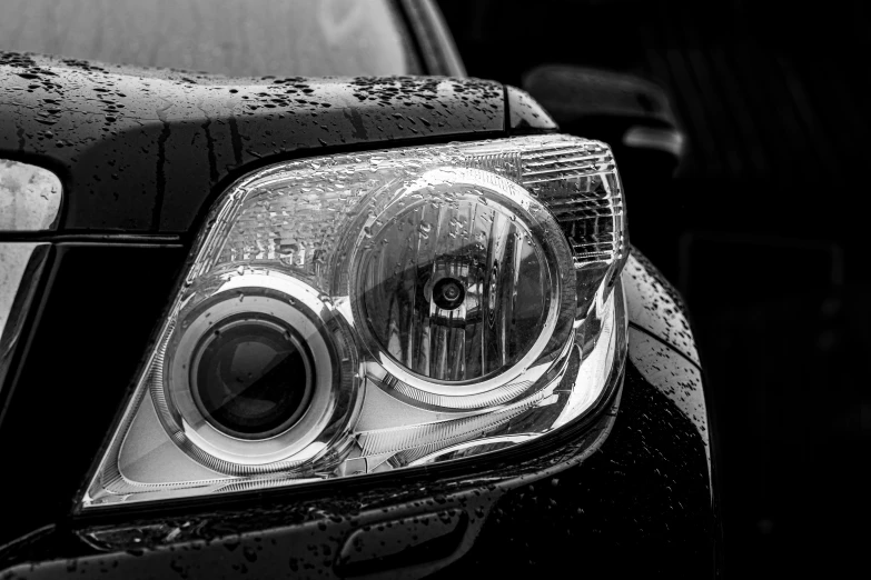 closeup on headlight of car, showing small dles of water on the windshield