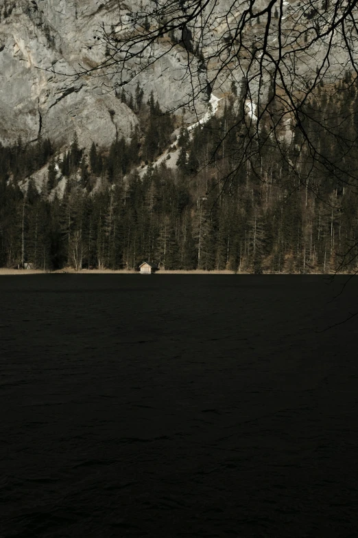 a cabin is seen on the side of a mountain lake
