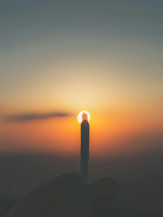 a person holding their cellphone at sunset