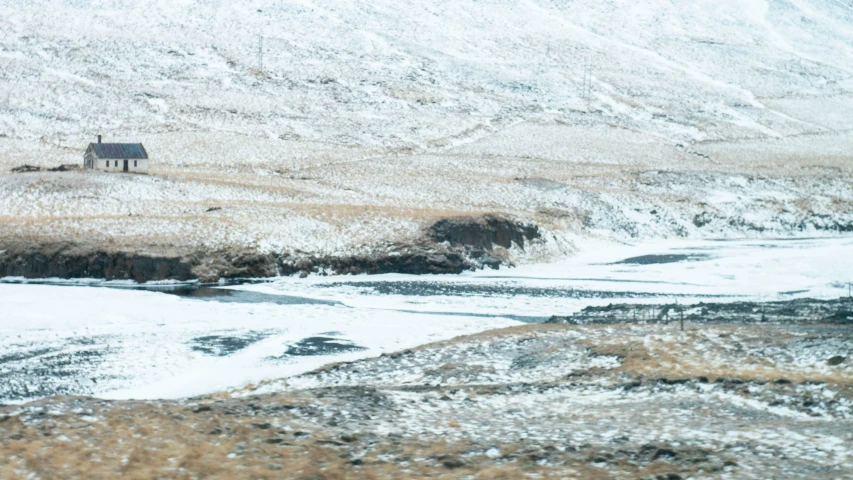 a snow covered hill and an old barn on it