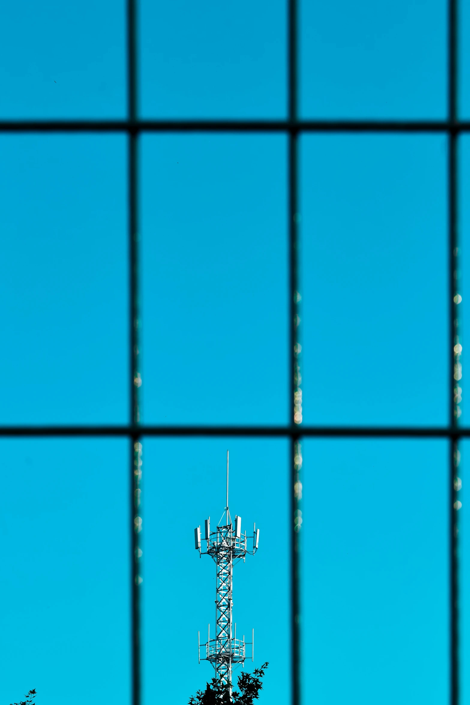 an antenna on top of a radio tower with a tree below it