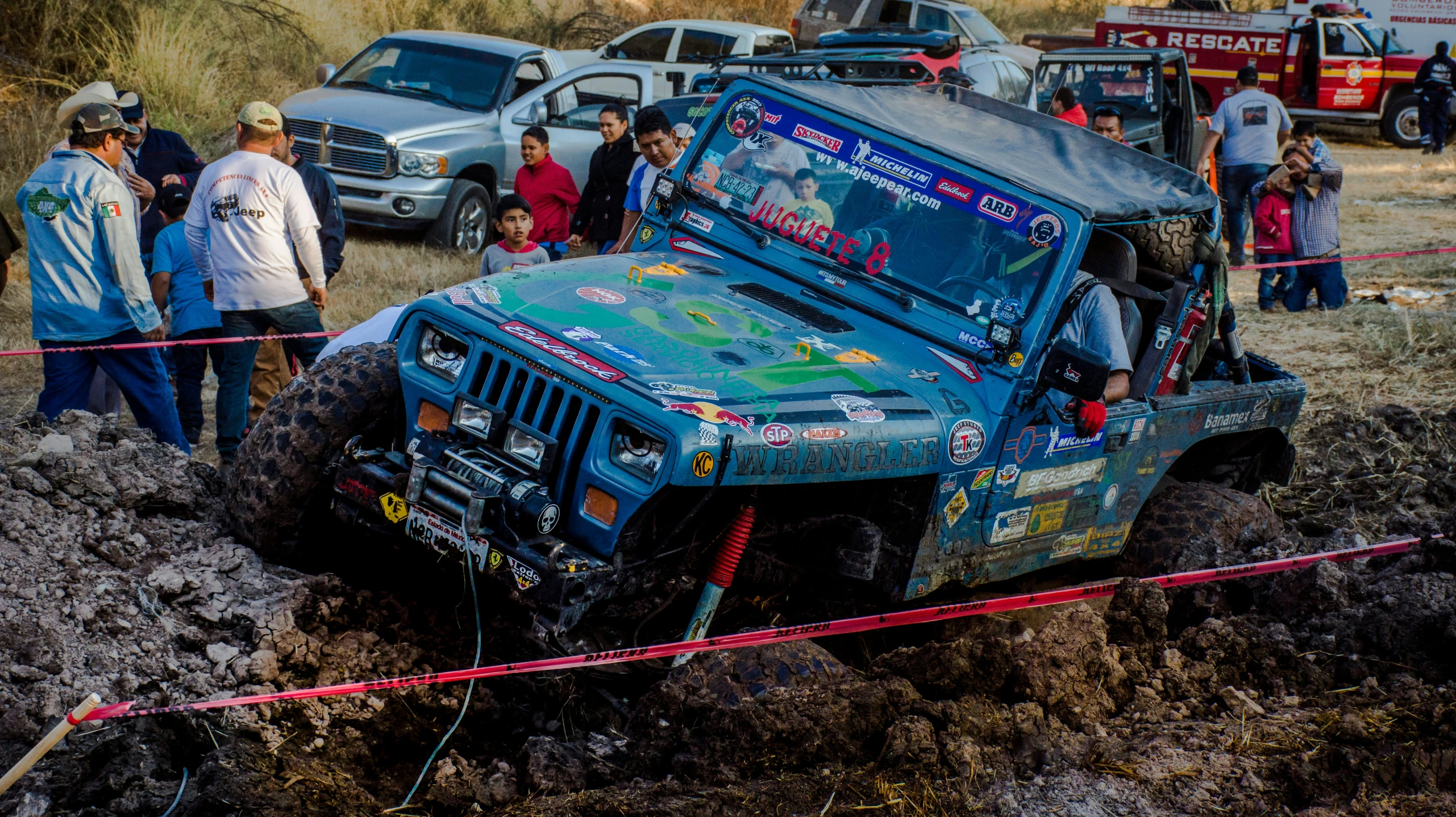 people standing next to vehicles while in the mud