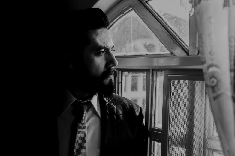 a man in a suit looking out of a window