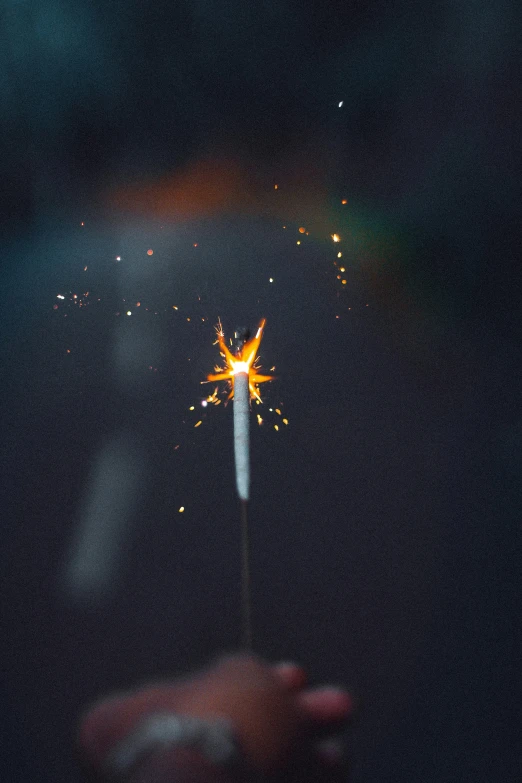 someone holding a lit sparkler with a blurry background