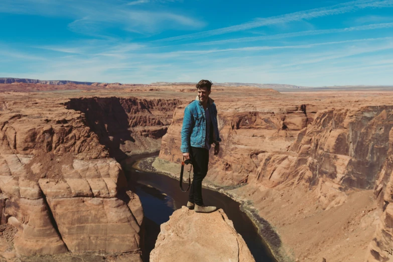 man standing on edge of cliff with cane looking down