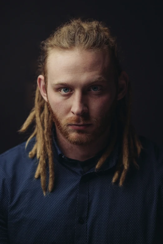 a man with dreadlocks on his face posing for a portrait