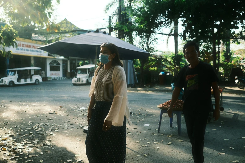 a girl standing under a black umbrella while two other people walk by