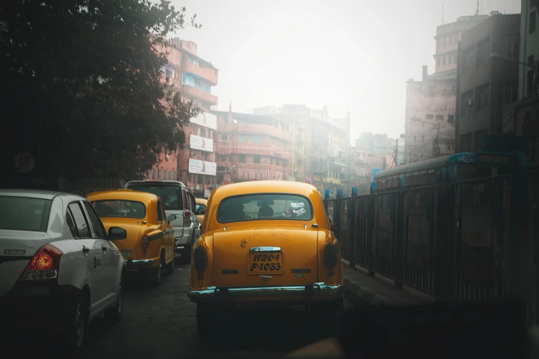 an old car and several cars on a street with buildings in the background