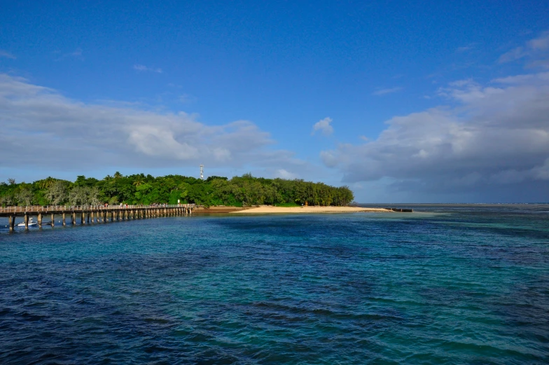 a long pier on a blue ocean with white buildings on the top