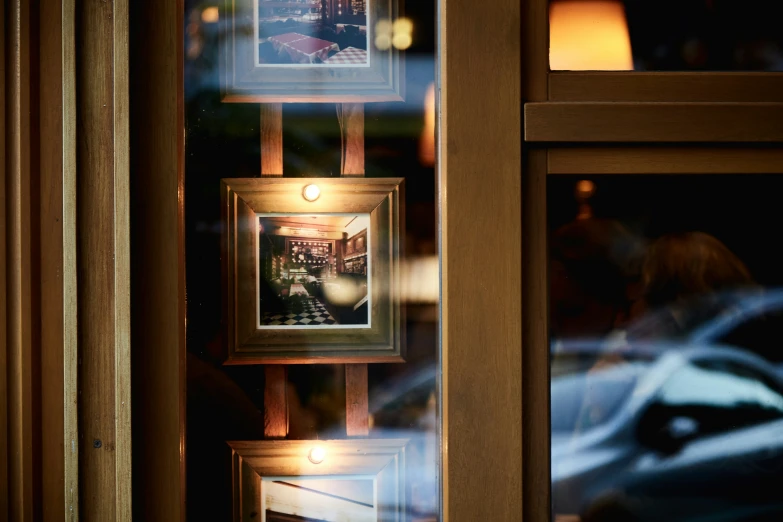 two framed pos hanging on a window with the reflection of a restaurant