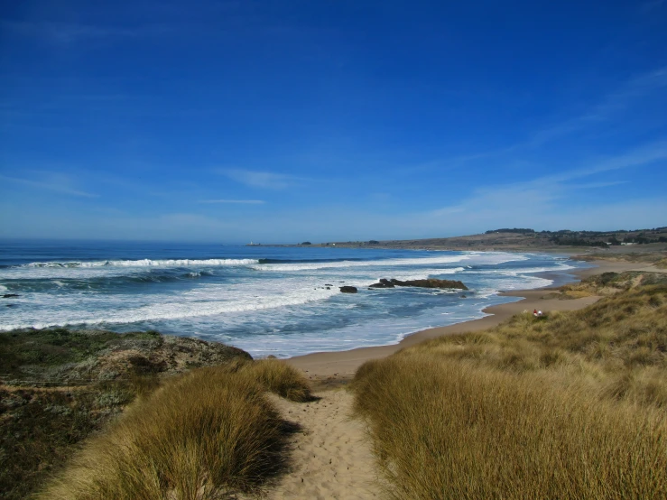 a very sandy beach by the ocean with a surfboard in the water