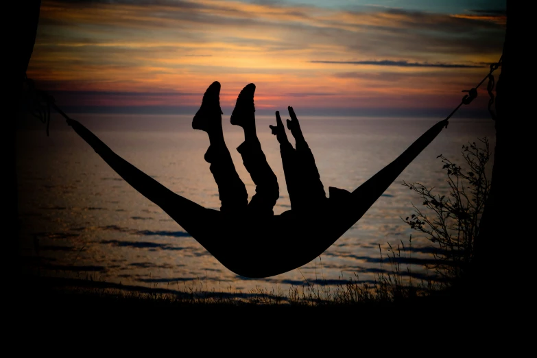 this is a sunset on the ocean with a hammock