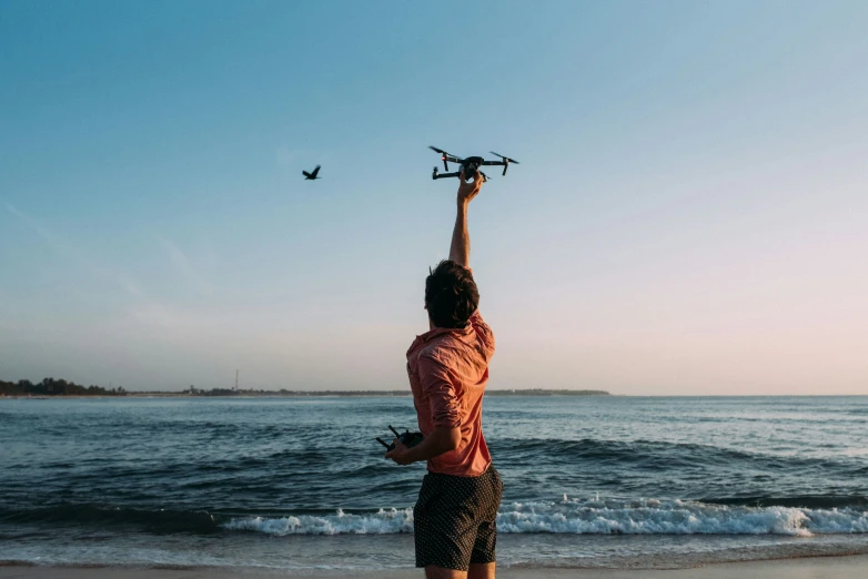 the person is flying a small device above the ocean