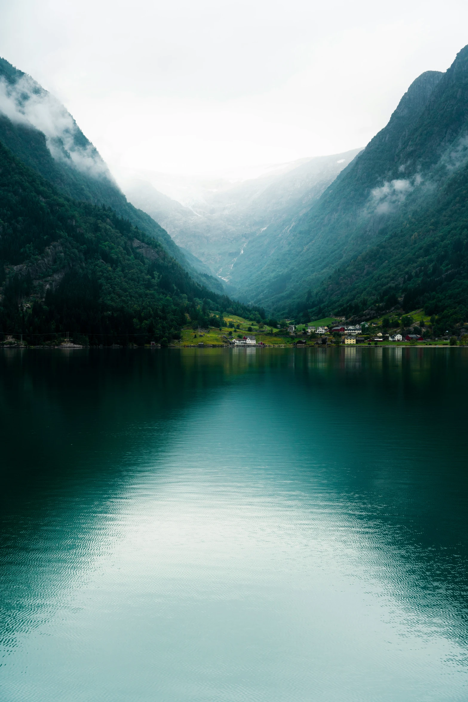 an empty lake surrounded by mountains and clouds