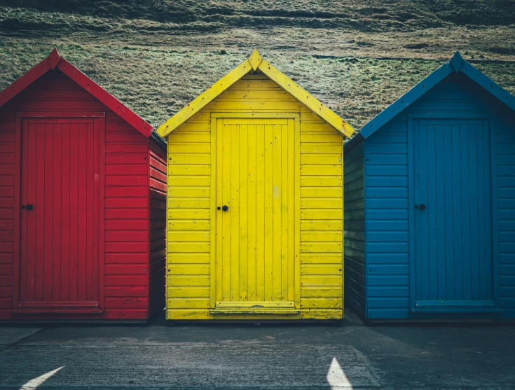 three rainbow beach huts sitting on the side of the road