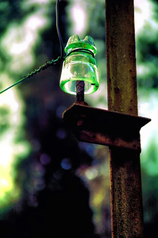 green glass object hanging from a wooden pole