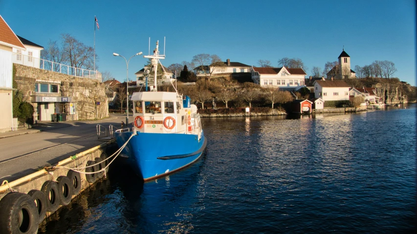 a blue boat is docked by some buildings and houses