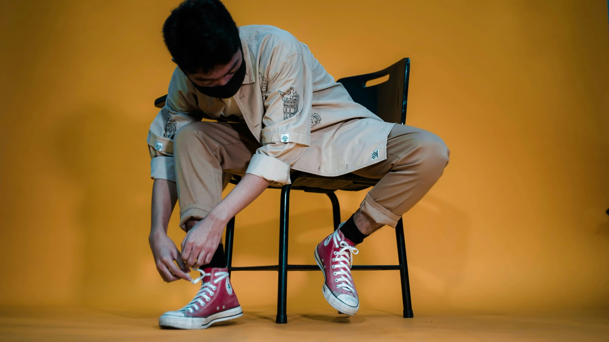 a man is sitting down with some converses on his feet