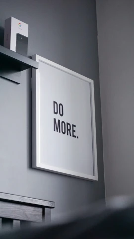 the print says do more in black on a wall