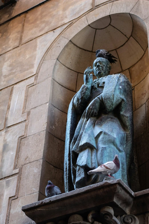 a statue sitting outside a tall building near birds