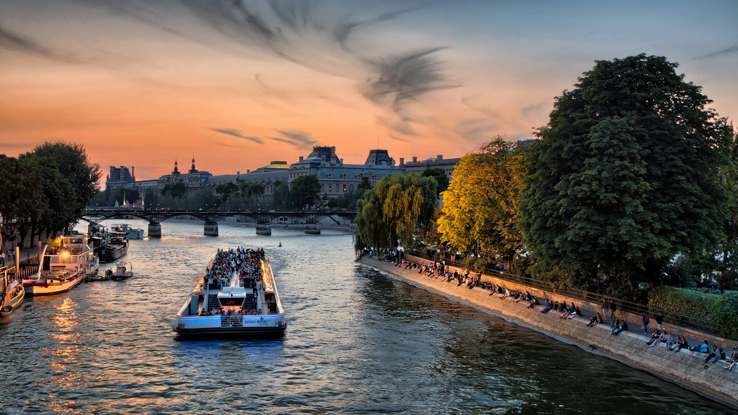 a boat rides down a canal with boats passing by