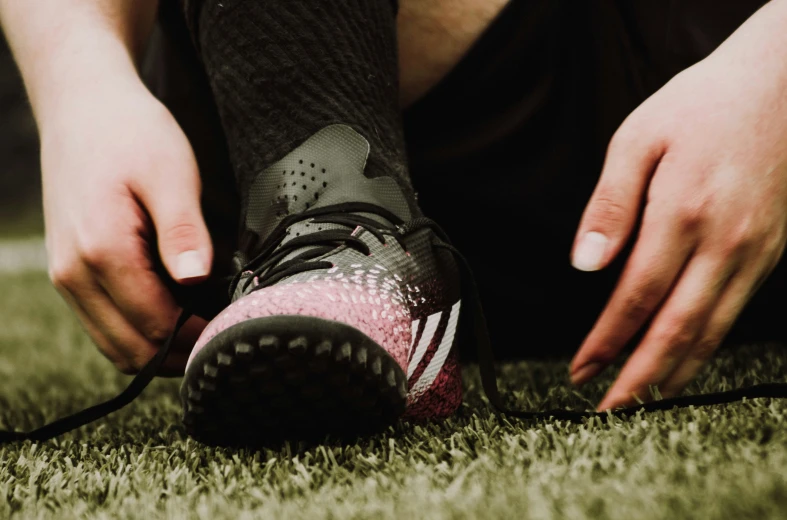 someone tying their shoe laces as they go on some grass