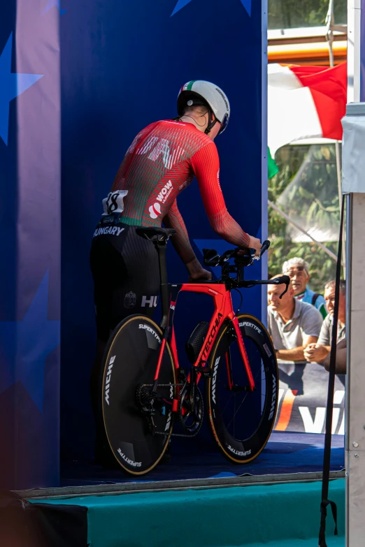 man in red cycling jersey preparing to ride his bike