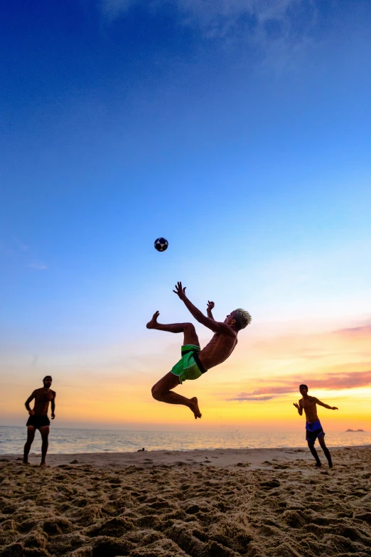 three men are playing volleyball on the beach