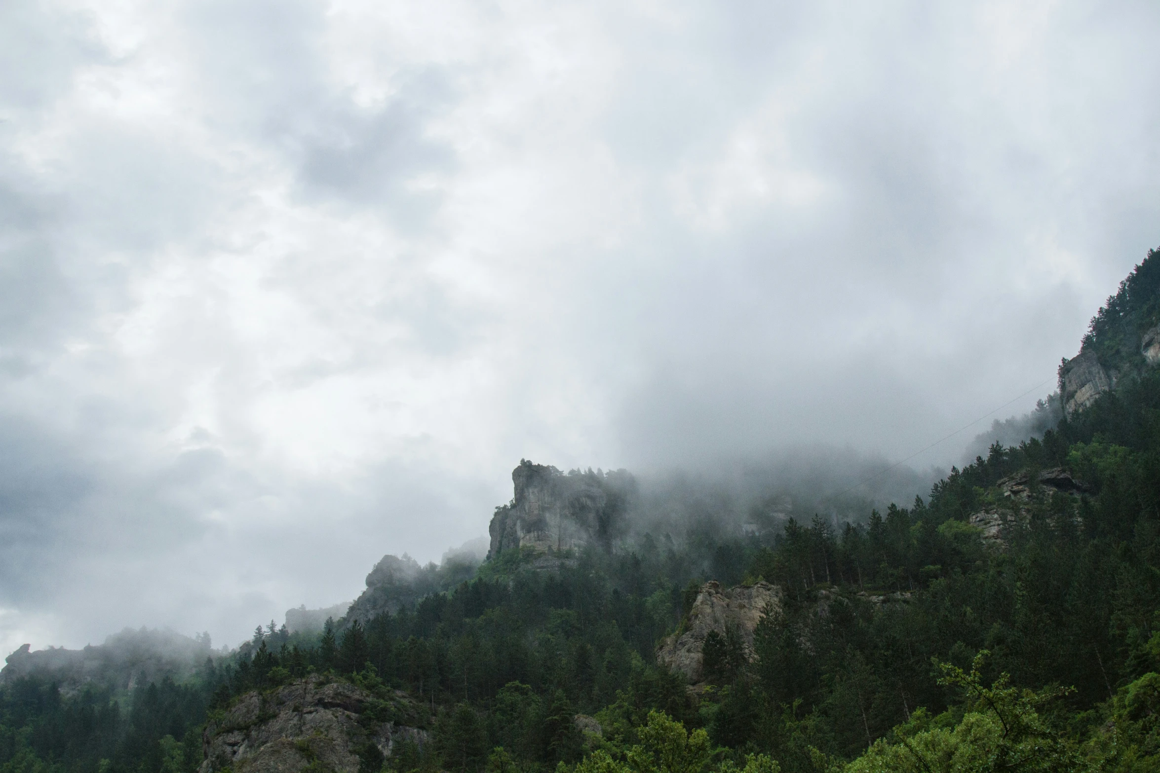 a boat on the water in front of a cloudy mountain