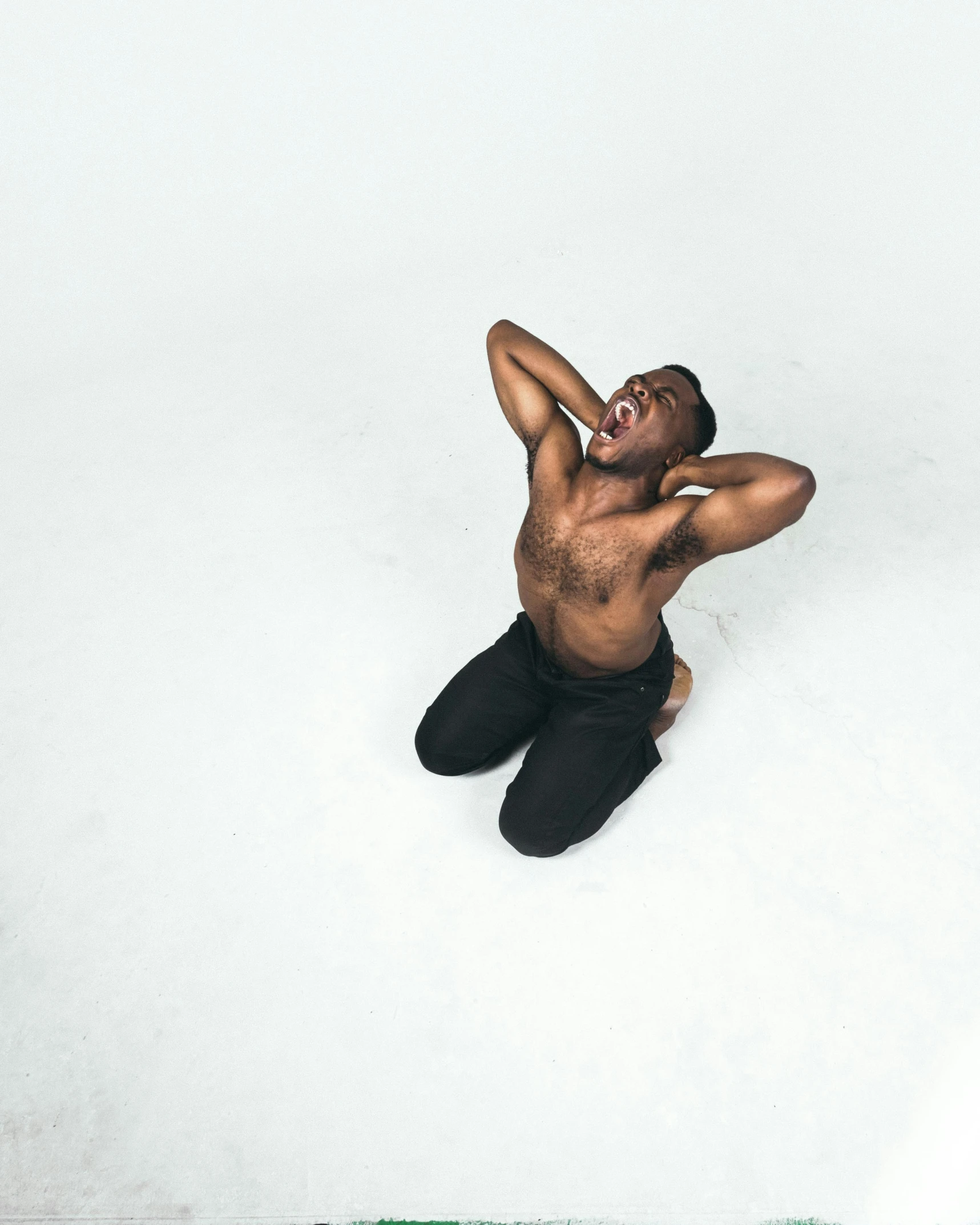 a young man sitting on the ground talking on a cell phone