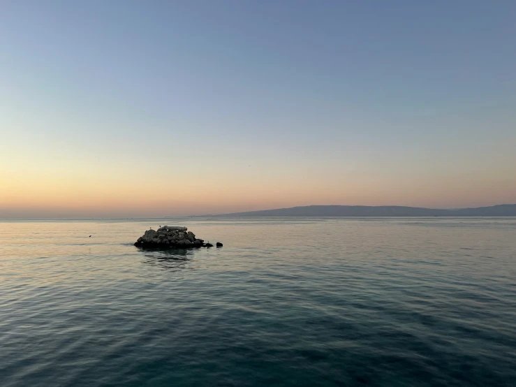 an island sits in the middle of the ocean at sunset