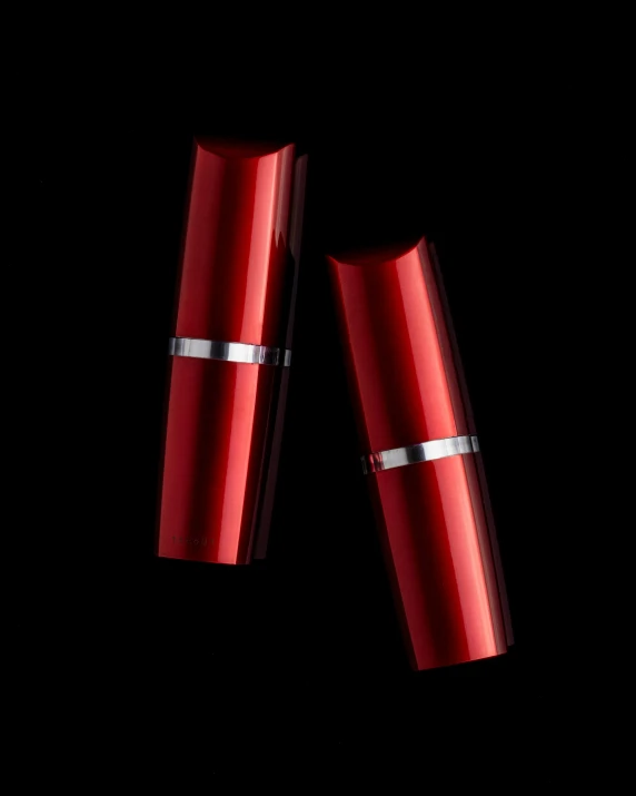 two red lipstick tubes with two shiny silver bands on the top of them