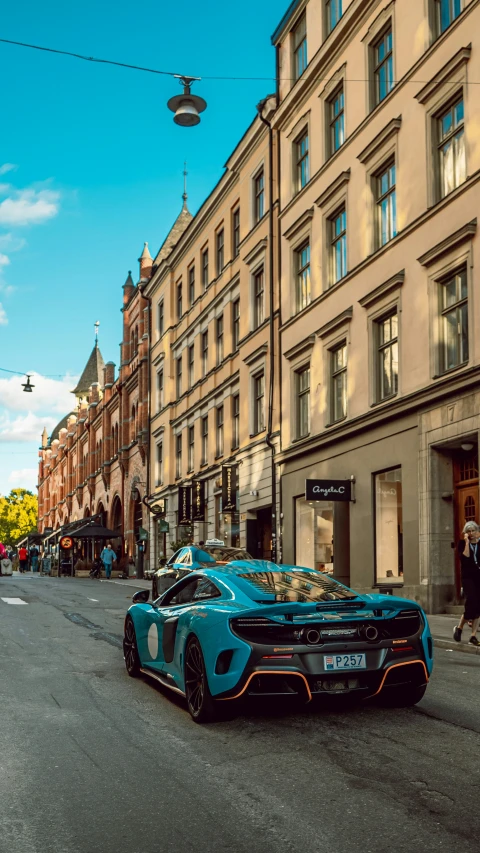 the car is blue with orange stripes and is parked on a street