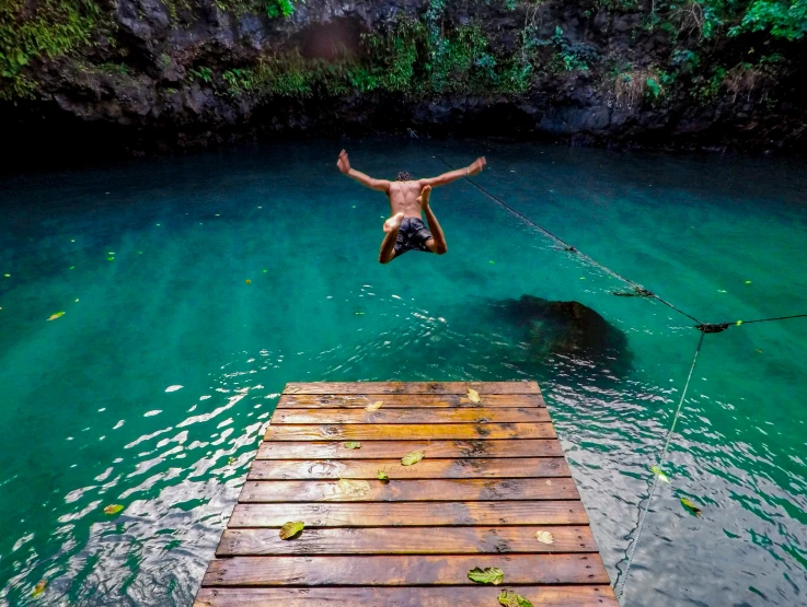 a man jumping off a dock into a river