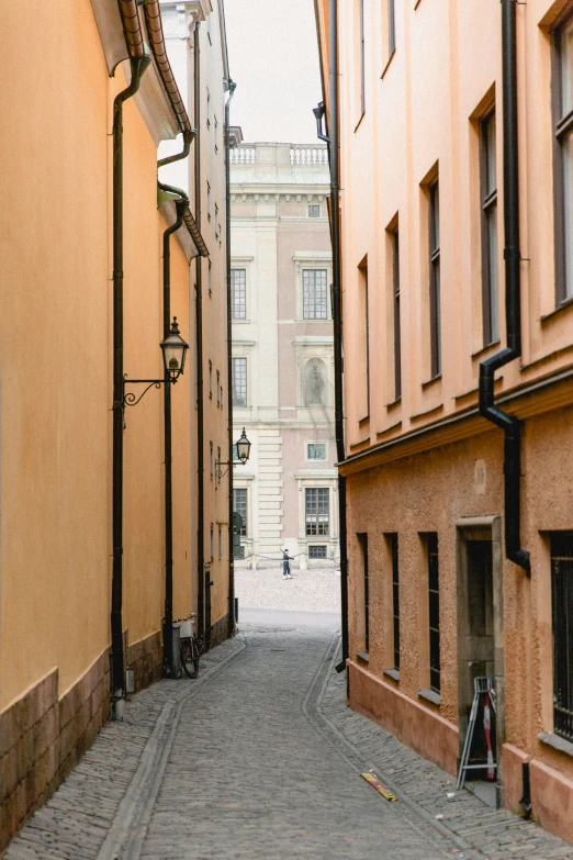 the view down a very narrow street with tall buildings on either side