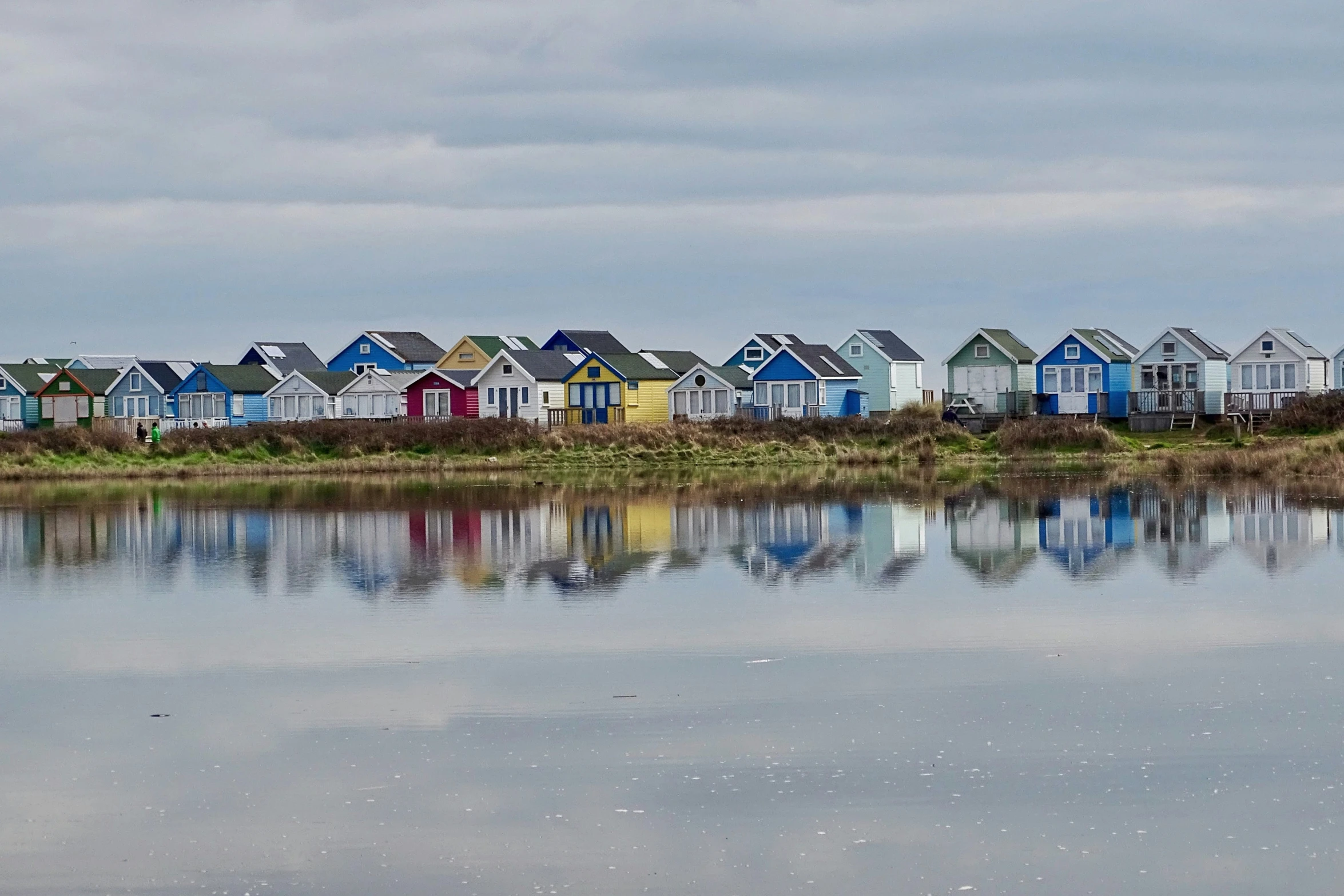 a bunch of houses sitting on a river bank by some grass