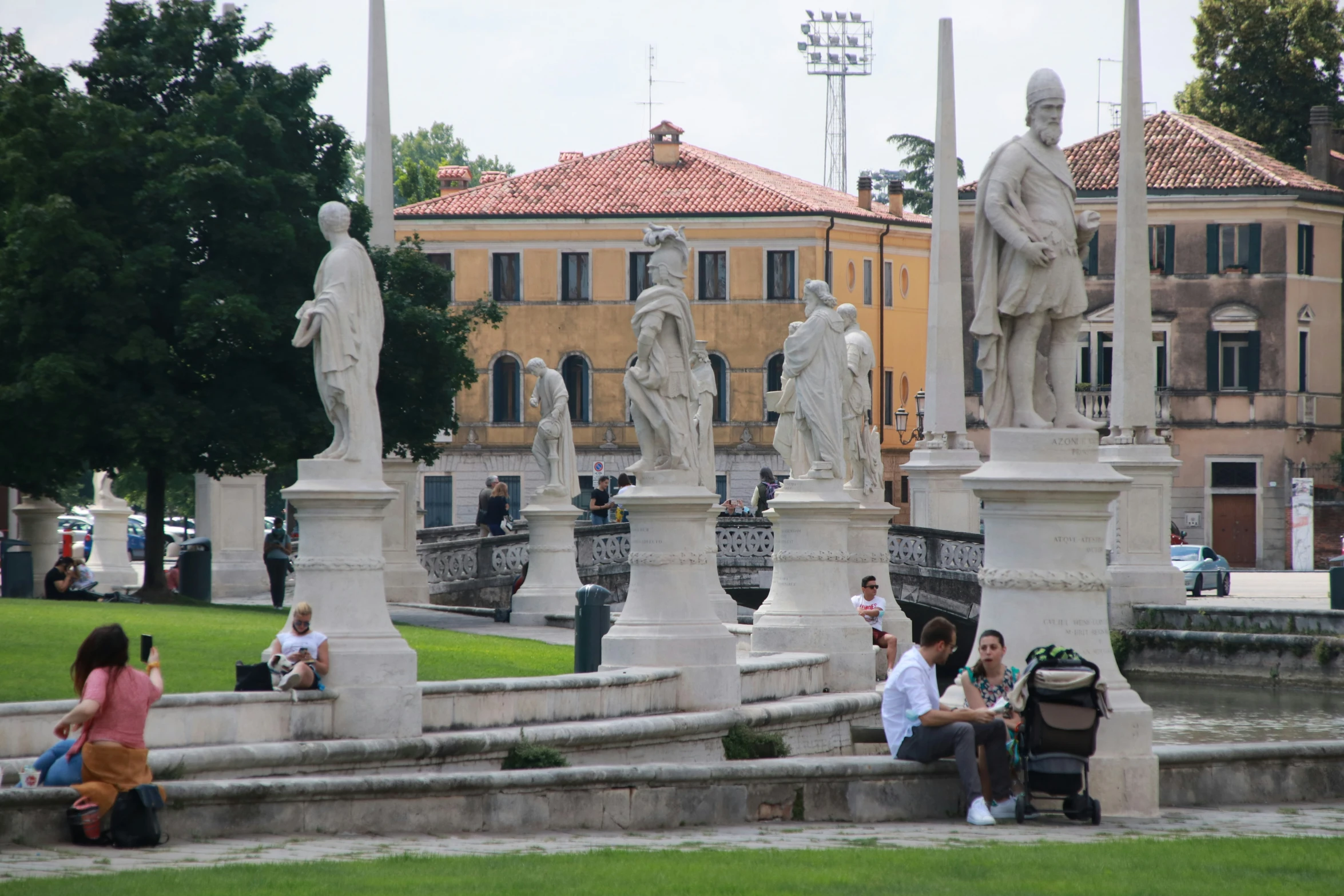 the people are sitting near many statues