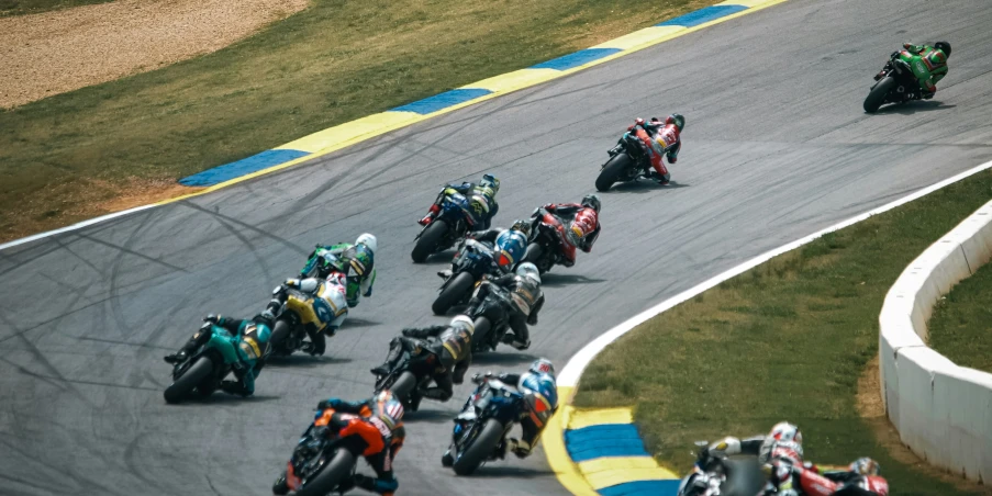 a group of people are racing motorcycles around a track
