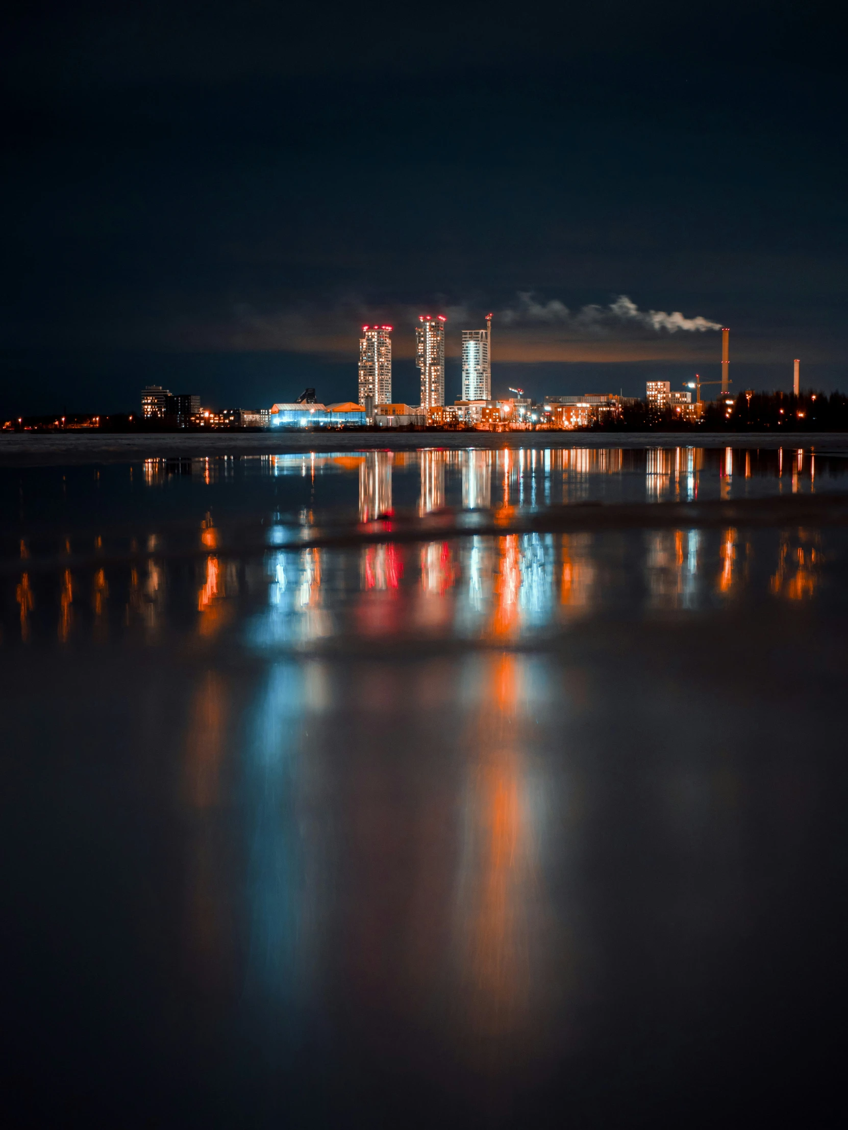 a lake is seen at night with smoke stacks