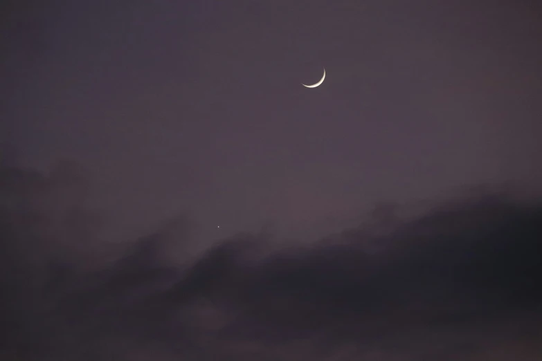 a view of a crescent at night from behind the clouds