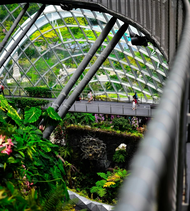 people walking under a glass structure and over a river