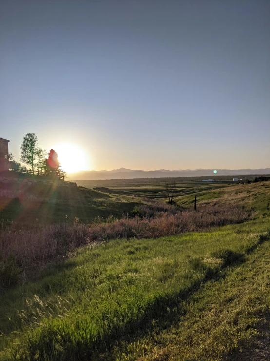 a grassy hill is in the distance with the sun shining