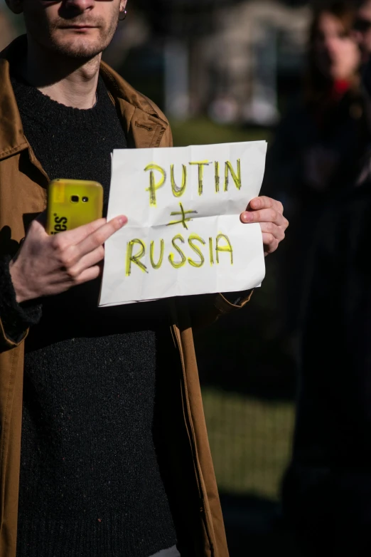 man holding up a sign with german writing on it