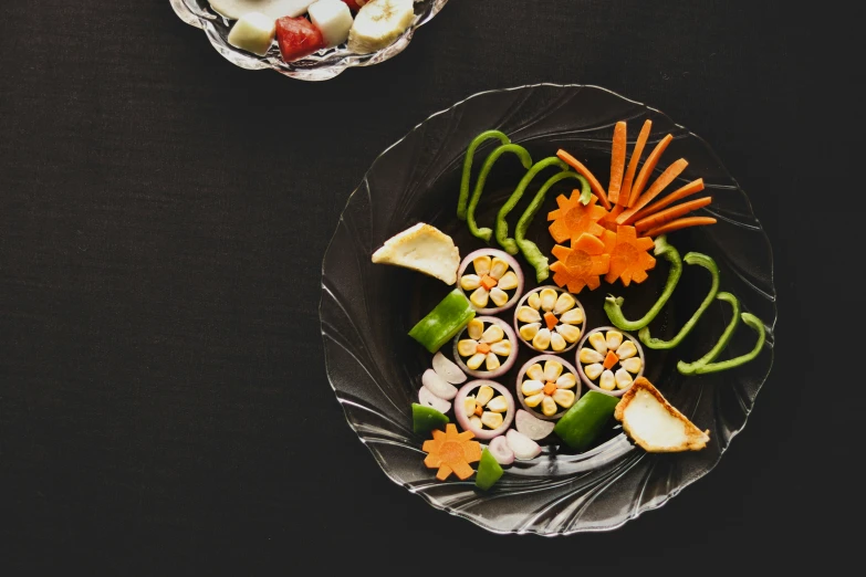 two plates with vegetables, fruits and ers on them