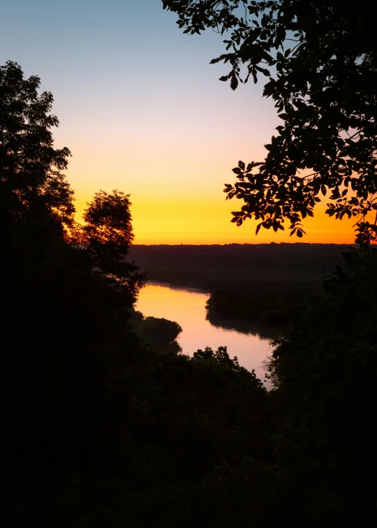 a picture taken at sunset with a tree near the river