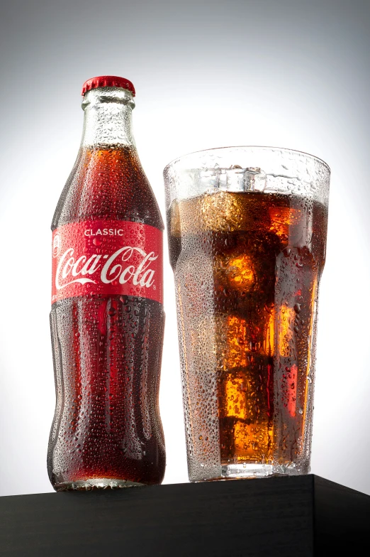 a coca cola glass and a full bottle are shown