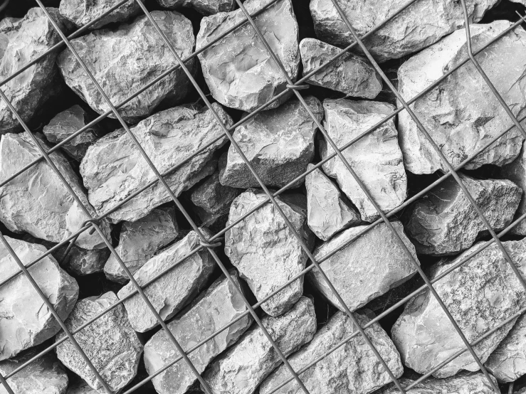 rocks piled up against a metal grid fence