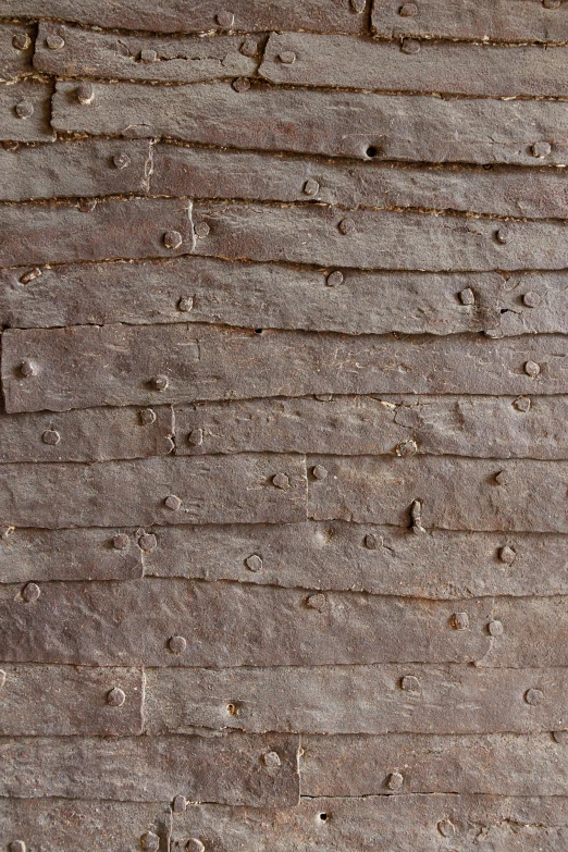 a brown wooden wall has holes and lines in it