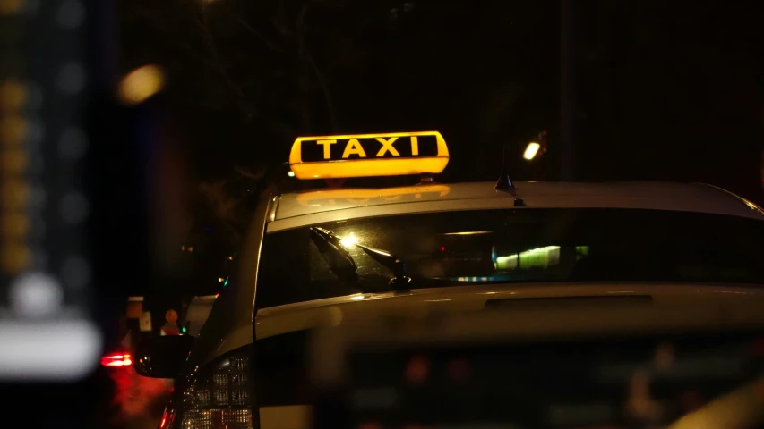 a taxi car is shown at night, with its yellow roof light on