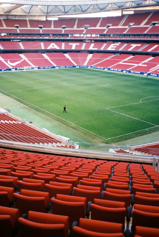 a large empty stadium with many seats and a player running